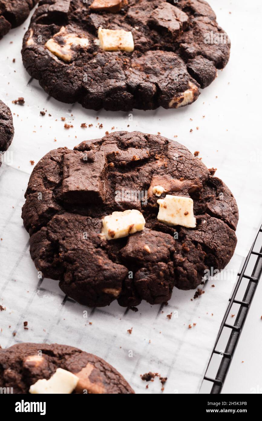 un primo piano verticale di più biscotti al cioccolato scuro su carta da forno Foto Stock