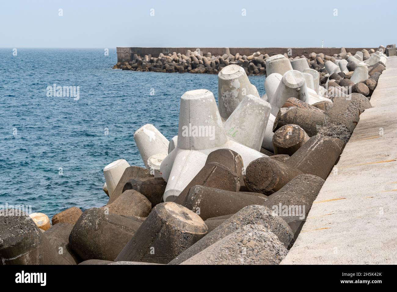 Protezione dalle acque frangibili sotto il cielo blu, blocchi solidi in cemento nel porto di Heraklion. Grecia. Foto Stock