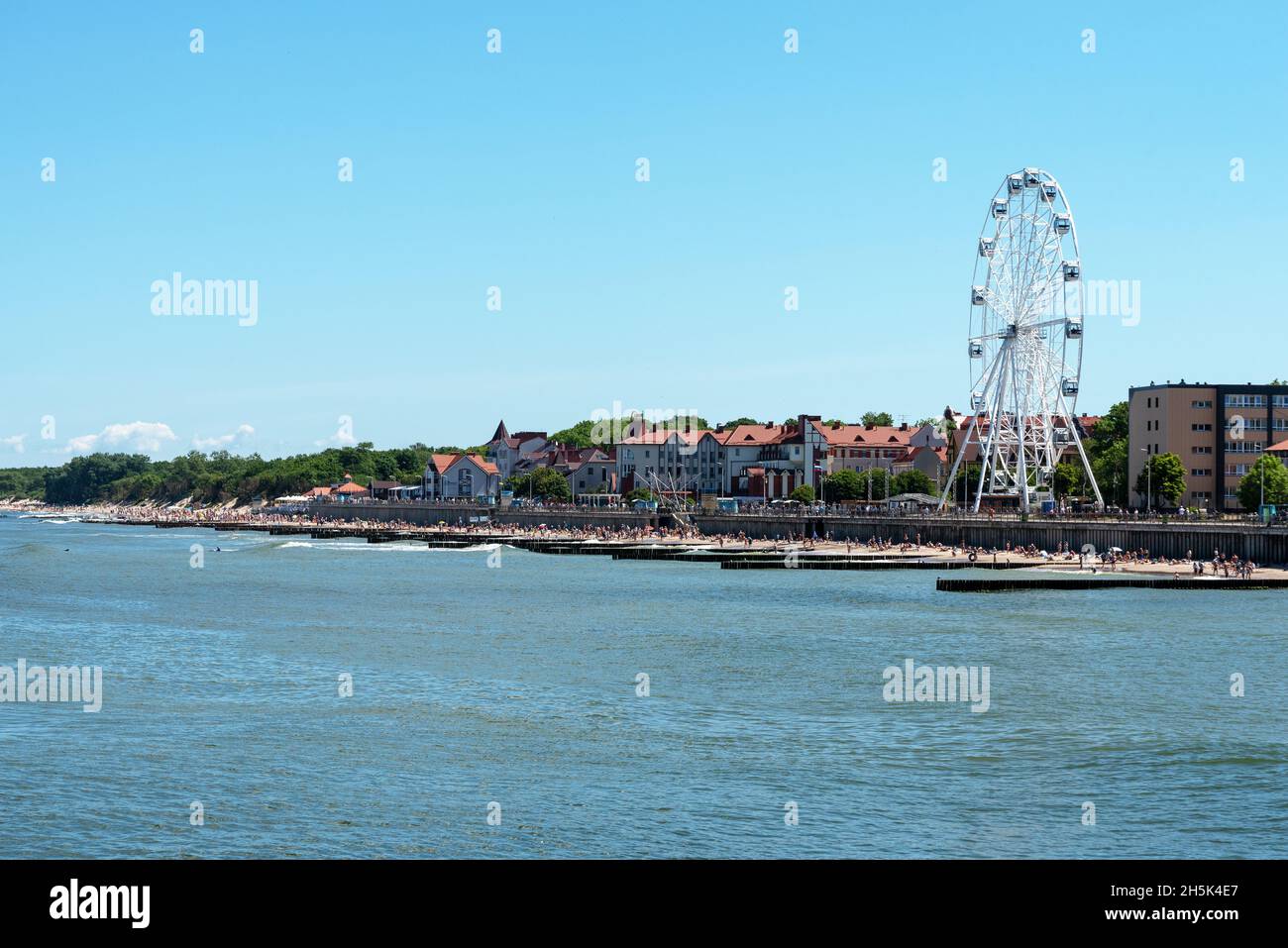 Zelenogradsk, Regione di Kaliningrad, Russia, giugno 2021. La linea costiera della città. Una nuova ruota panoramica. Molte persone si rilassano sulla spiaggia Foto Stock