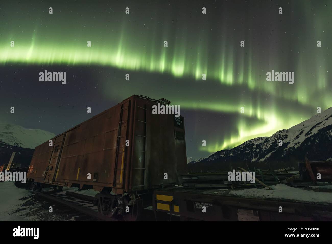 Aurora borelais mostra sul fiume Twentymile con vagoni ferroviari e montagne a Girdwood; Alaska, Stati Uniti d'America Foto Stock