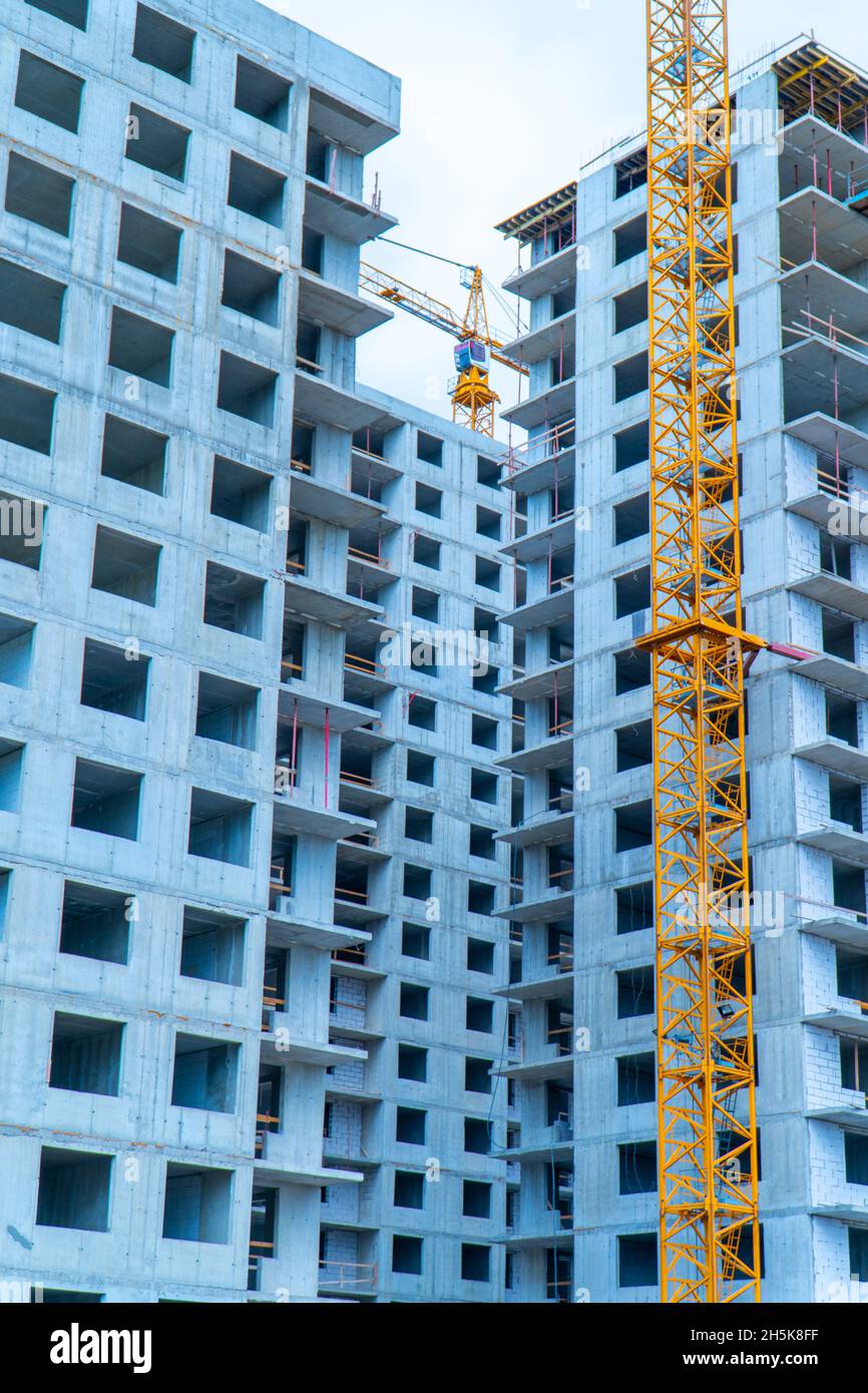 Gru gialla di fronte all'edificio in cemento in costruzione Foto Stock