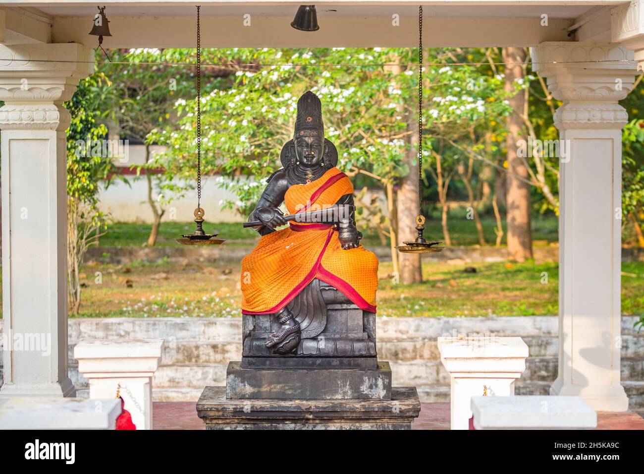 Santuario indù con una statua di una divinità avvolta in seta arancione nel villaggio rurale a CGH terra proprietà di Mantra Koodam in Kumbakonam Foto Stock