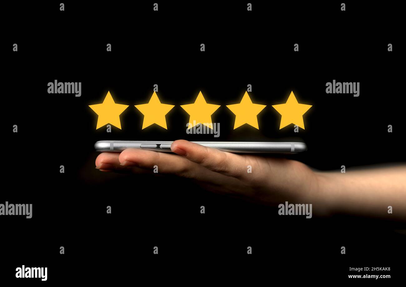 Revisione del cliente. Mano con il telefono cellulare, smartphone moderno con icona a forma di stella dorata. Soddisfazione, background del sondaggio di feedback. L'utente dà la valutazione, in linea a. Foto Stock