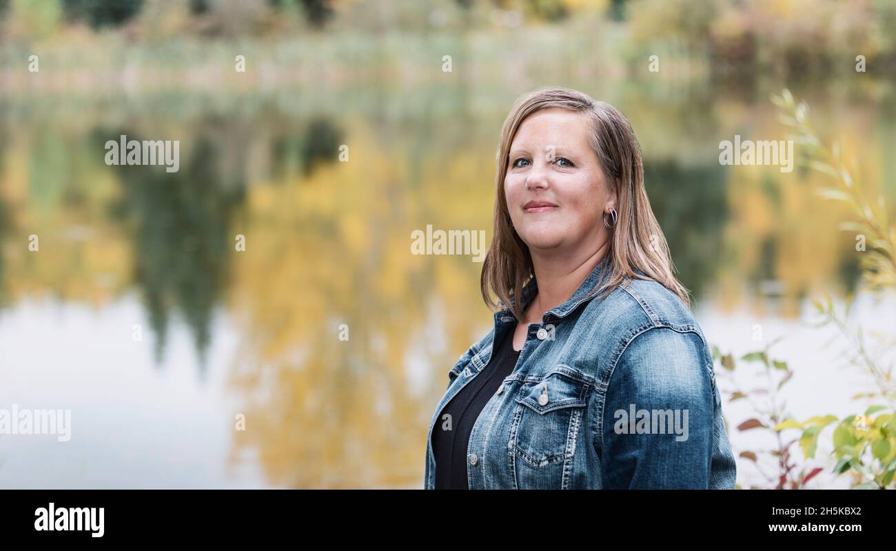 Una donna che si gode di tempo all'aria aperta in un parco cittadino con un lago sullo sfondo; Edmonton, Alberta, Canada Foto Stock