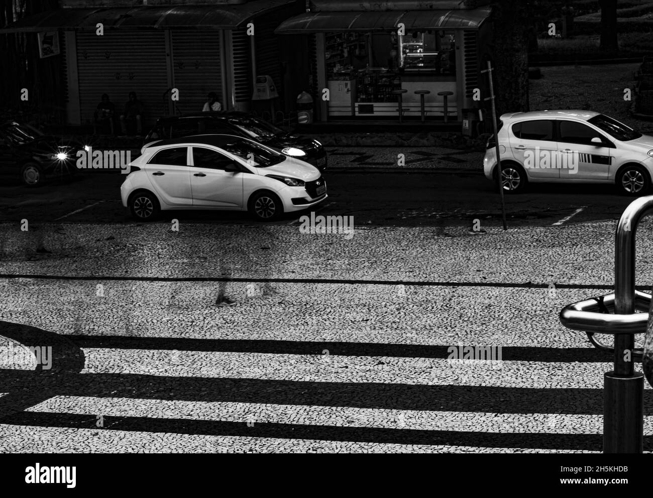 Foto in scala di grigi di auto che attraversano la strada durante la pioggia Foto Stock