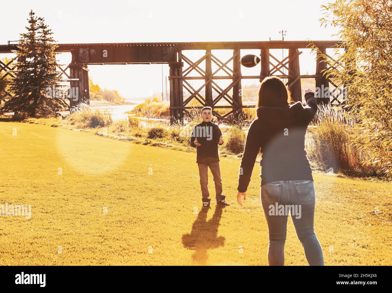 Madre che lancia un calcio con suo figlio in una bella giornata autunnale in un parco cittadino; St. Alberta, Alberta, Canada Foto Stock