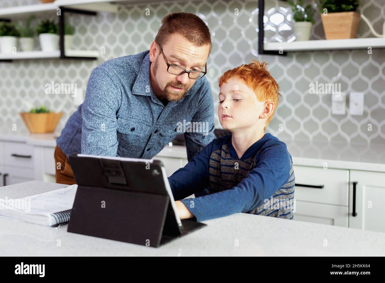 Padre che aiuta il figlio con i compiti nella cucina domestica; Edmonton, Alberta, Canada Foto Stock
