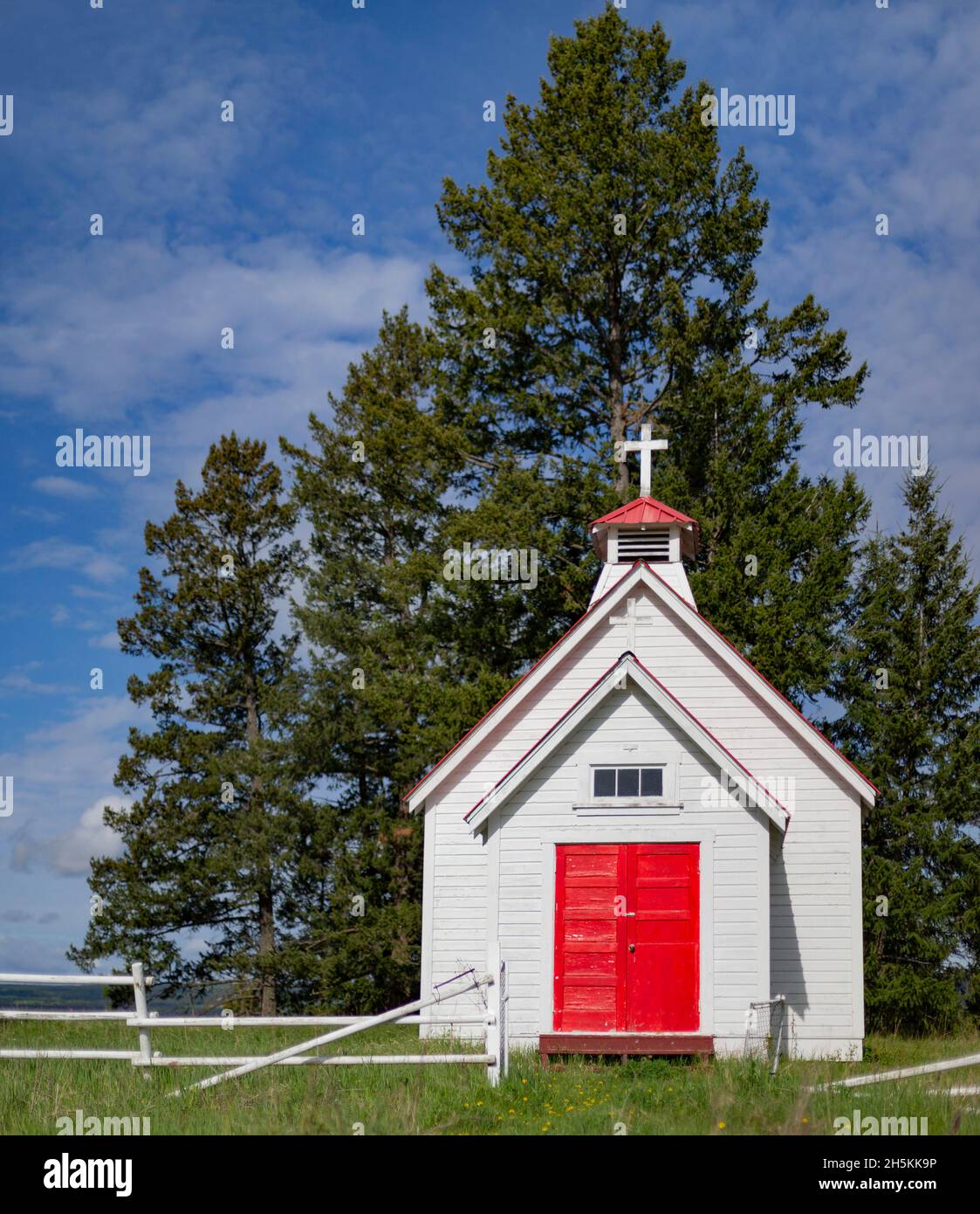 Una piccola chiesa di campagna bianca con porte rosse e una croce sulla cima; Columbia Britannica, Canada Foto Stock