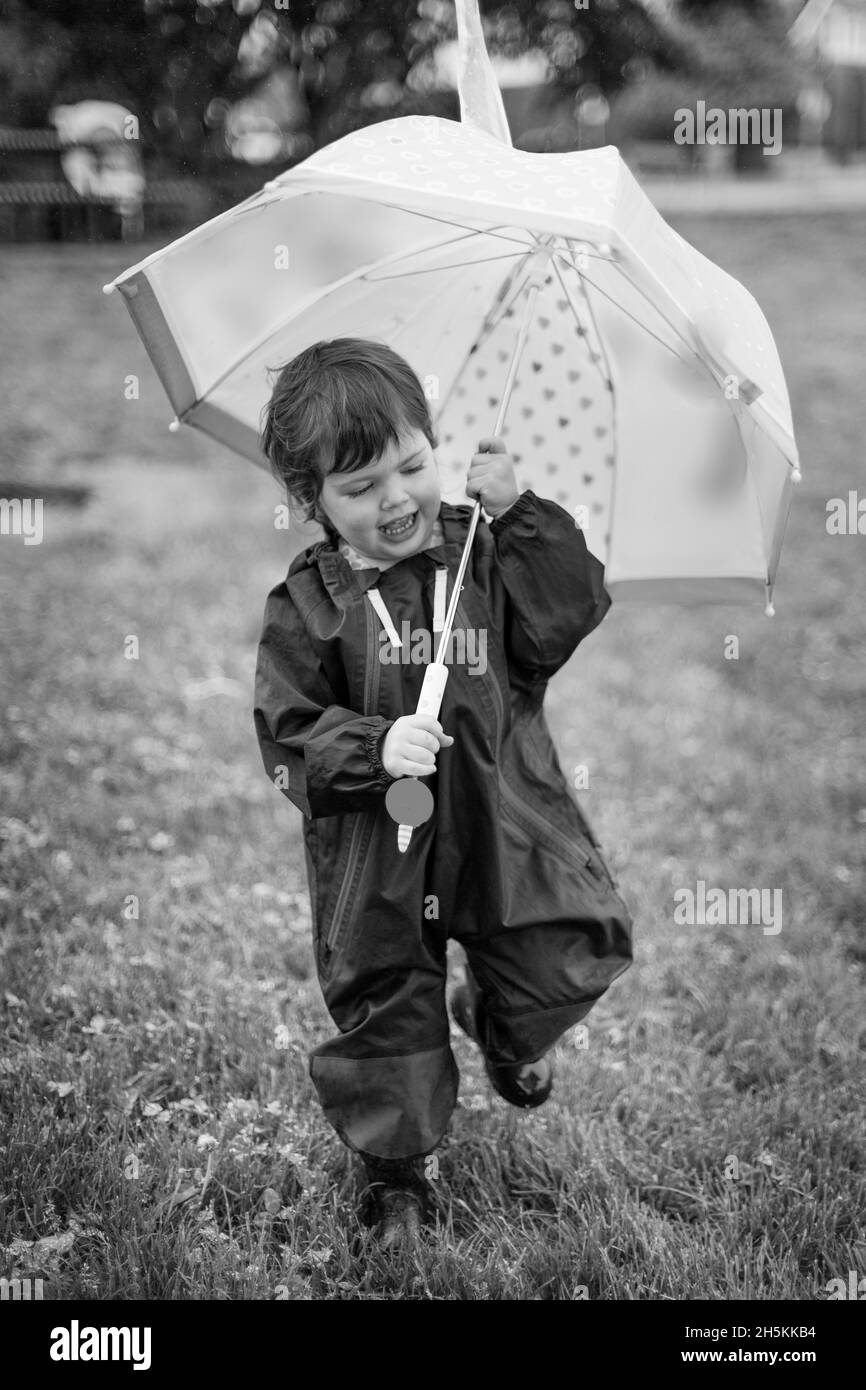 Ragazza preschooler che cammina in un parco con un ombrello; North Vancouver, British Columbia, Canada Foto Stock