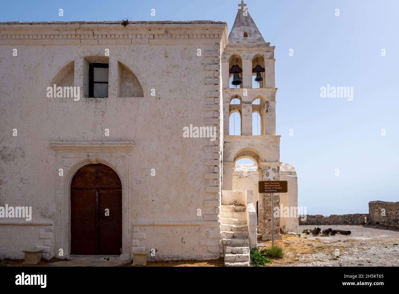 Panagia Myrtidiotissa antica chiesa greco-ortodossa medievale a Chora Kythira isola, Kithira, Grecia. Belfry due campane pietra edificio blu cielo backgr Foto Stock