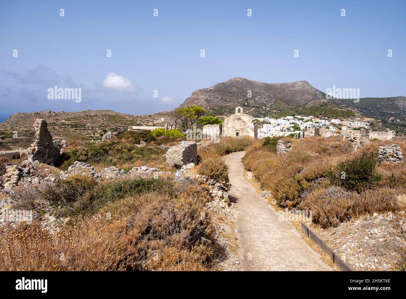 Sulla strada per l'antico castello veneziano di pietra tra le rovine di Fortezza all'isola di Kythira, Grecia. Edifici cielo blu, montagne e piante secche Foto Stock