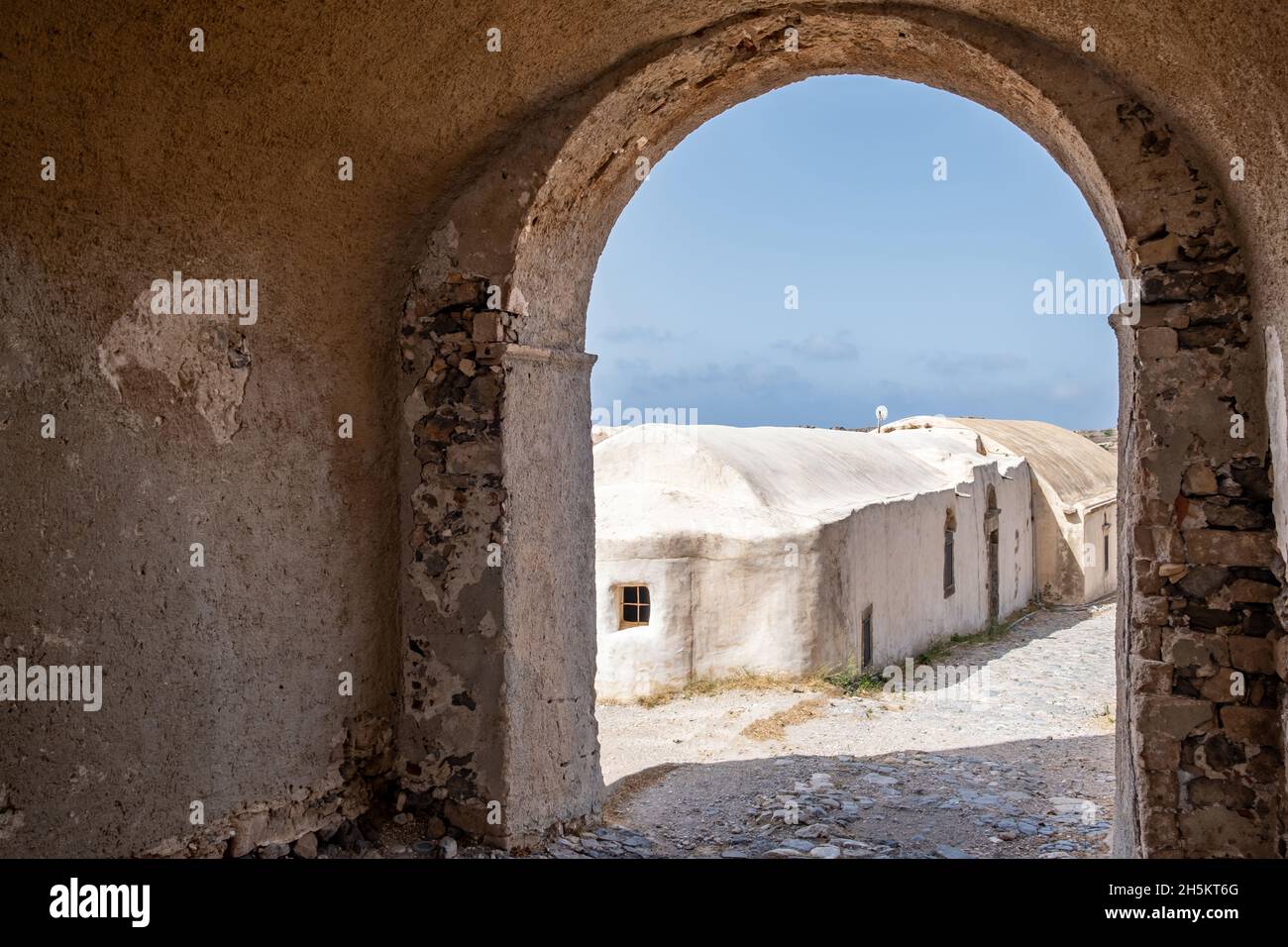 Isola di Kythira, Grecia. Castello veneziano Fortezza, muri in pietra e un arco, vista dall'apertura ad un vecchio edificio e cielo blu, giorno di sole Foto Stock