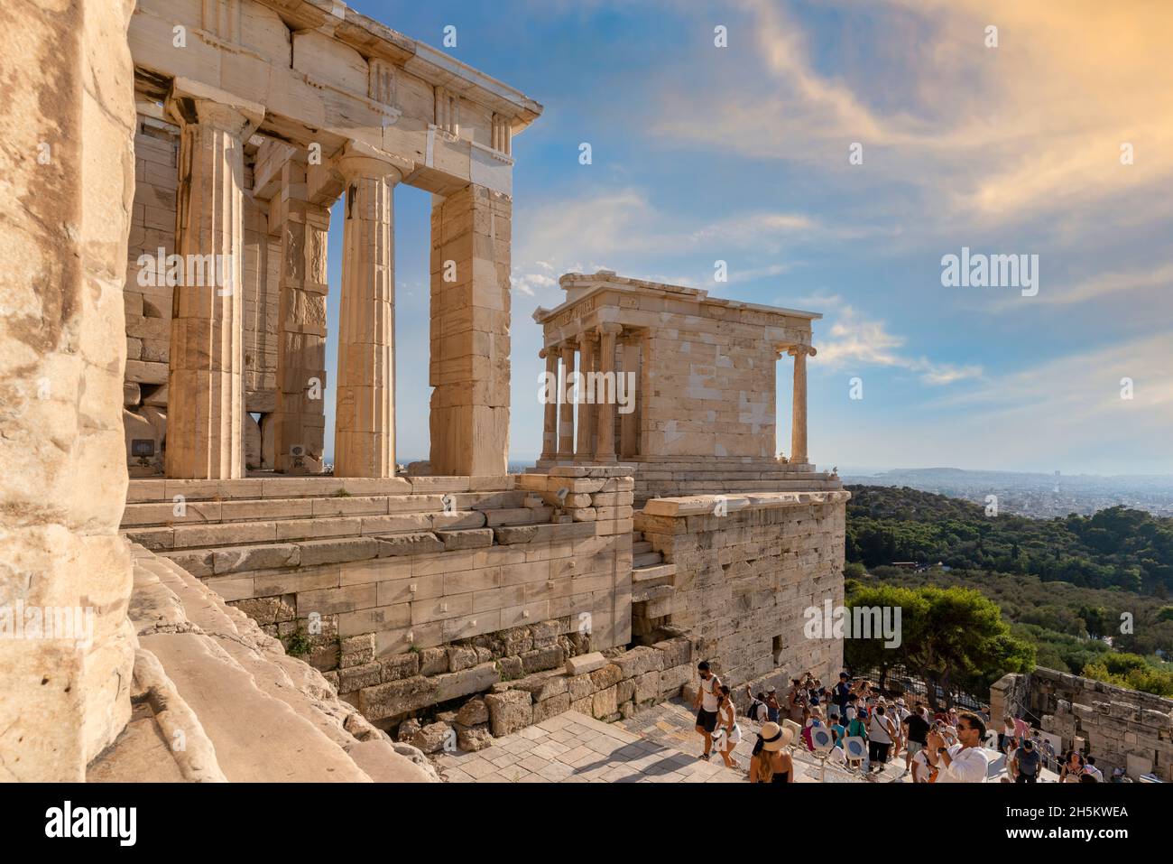Il Tempio di Atena Nike all'angolo sud-ovest dell'Acropoli a destra dell'ingresso, il Propylea. Giorno di sole, cielo blu, nuvole colorate Foto Stock