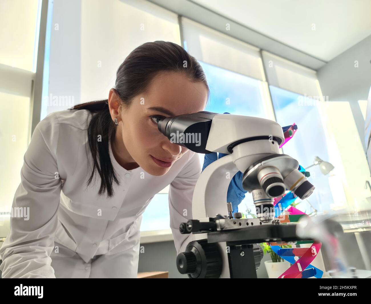Chimico scienziato femminile che guarda attraverso il microscopio in laboratorio Foto Stock