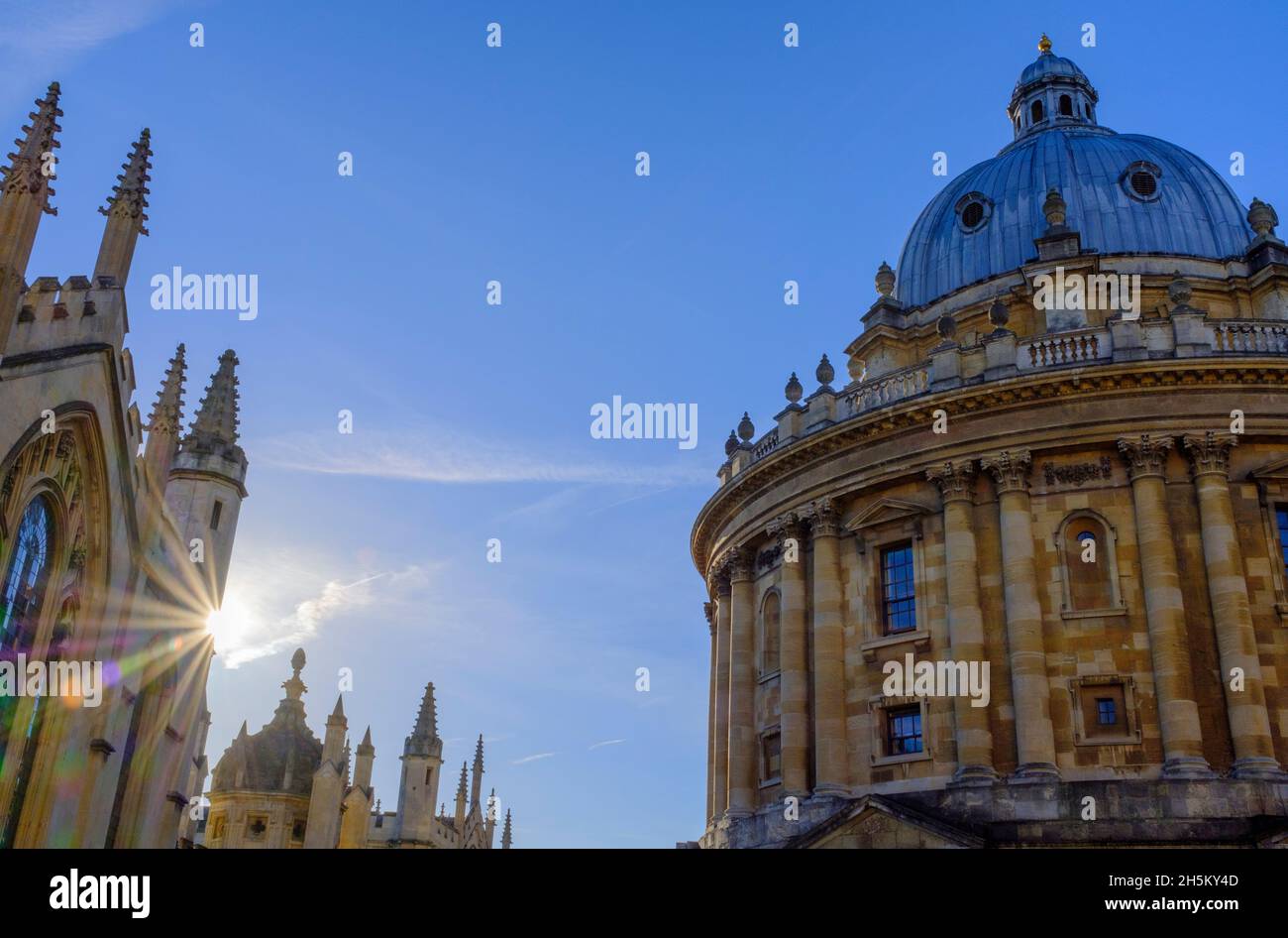 I raggi del sole adornano il lato del college All Souls e tra la Bodleian Library di Oxford bagnata dalla luce d'inverno dorata del mattino presto. Foto Stock