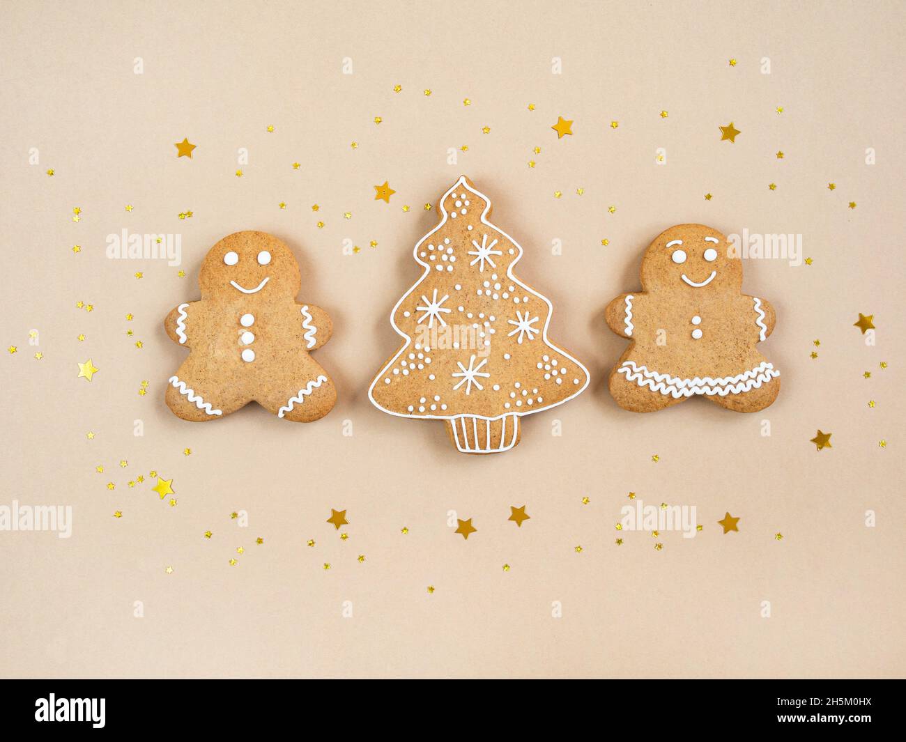 Felice anno nuovo o biglietto di Natale, coppia di pan di zenzero - uomo e donna, albero di Natale e stelle luccicanti dorate su sfondo beige. Felice concetto di famiglia Foto Stock