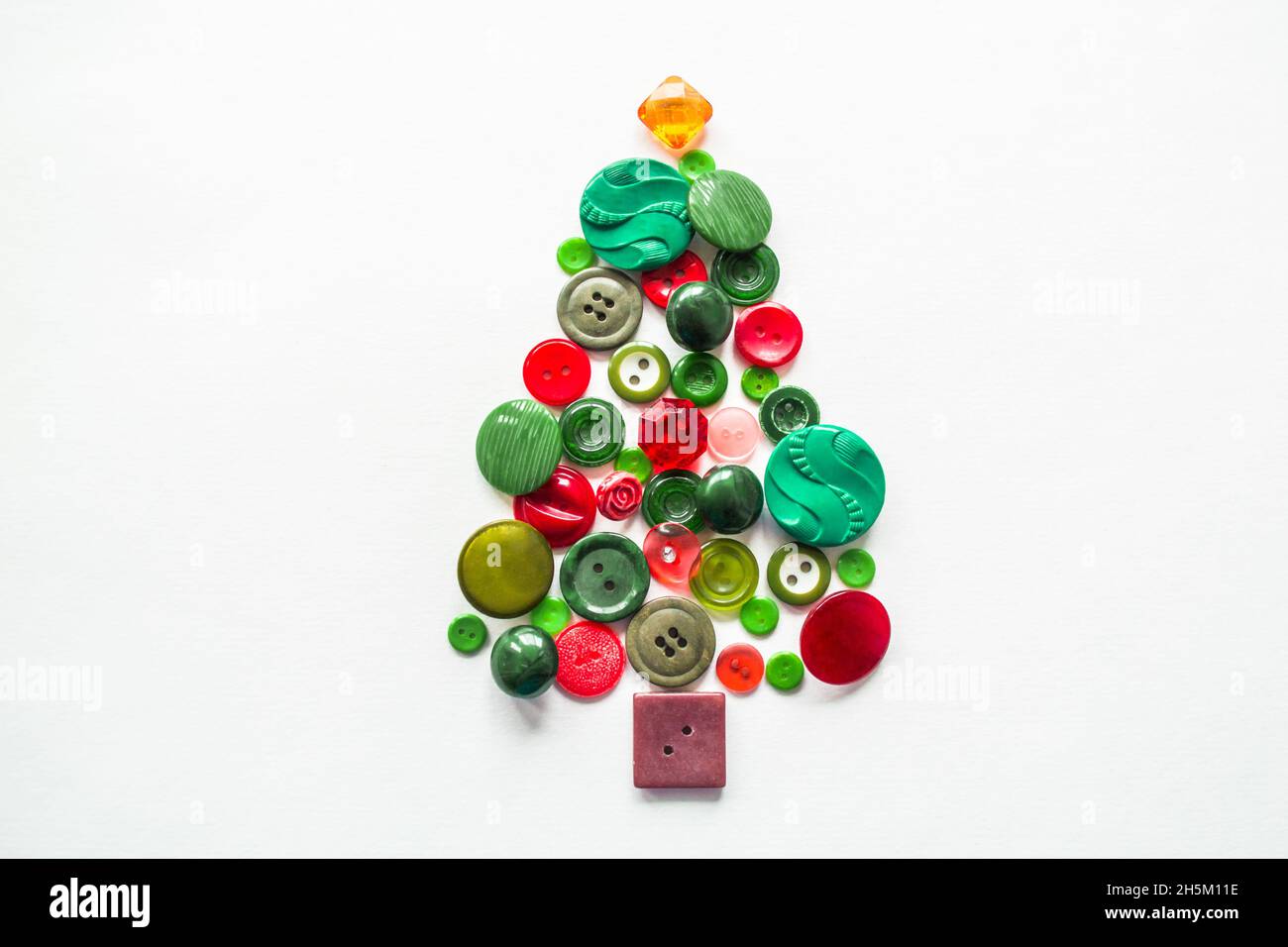 Un albero di Natale fatto di pulsanti di colore verde, rosso. Sfondo bianco, spazio copia. Concetto creativo di Natale. Foto Stock