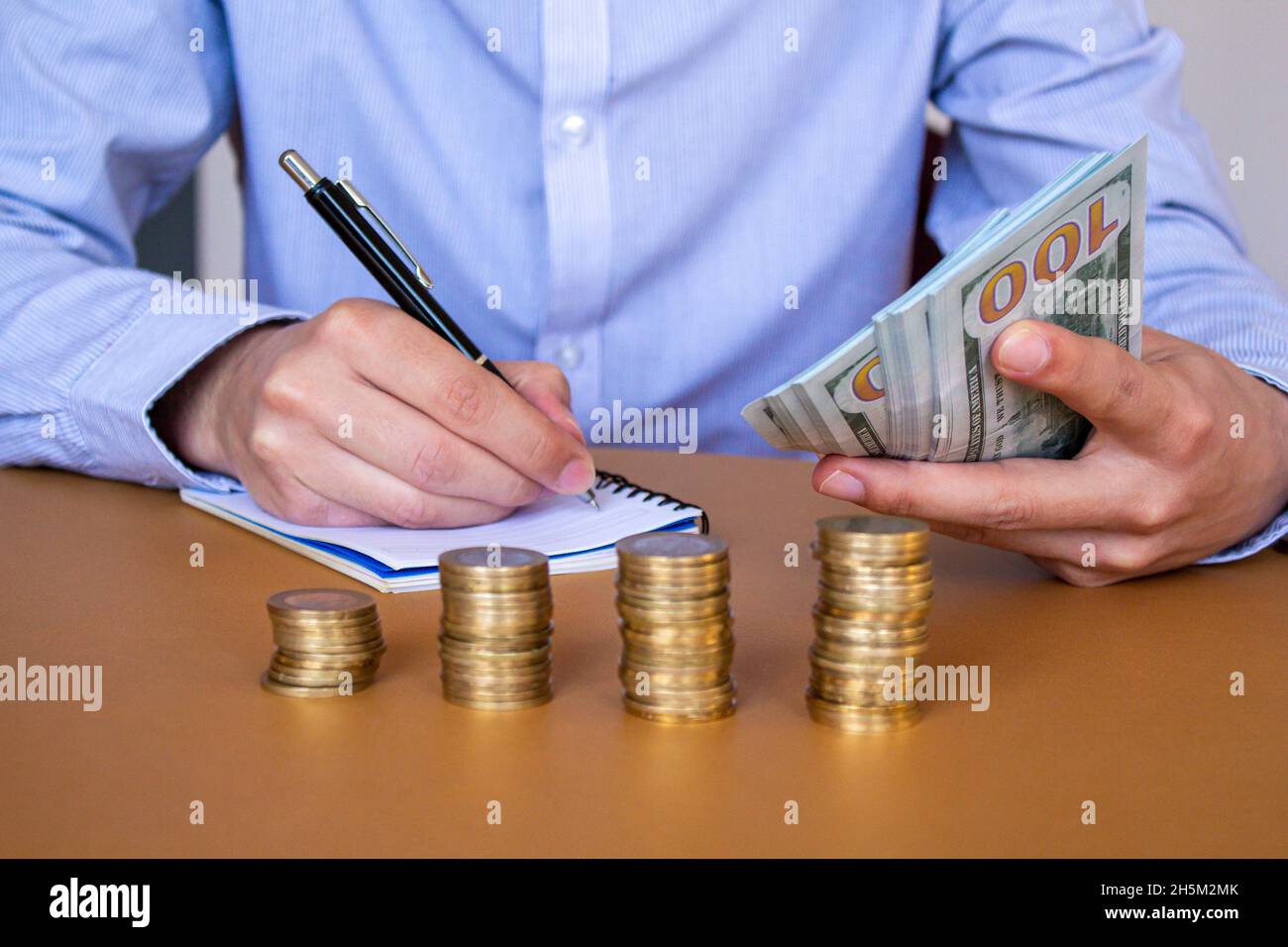 Uomo d'affari che conta i soldi e prende le note. Calcolo di profitti e perdite. Concetto di risparmio di denaro. Foto concetto bollette alte. Foto Stock