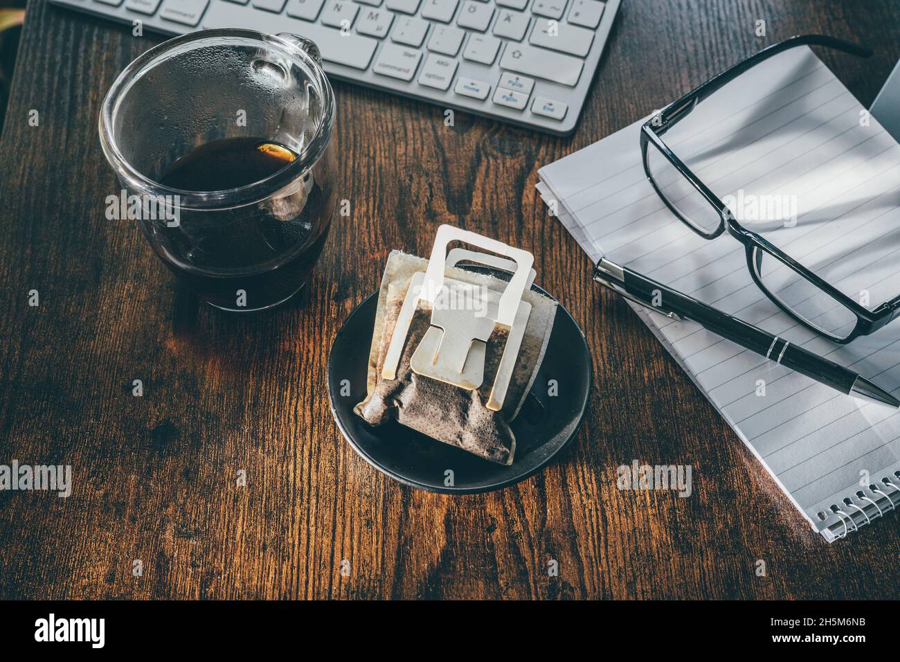 Usato sacchetto di caffè gocciolante sul tavolo da ufficio Foto Stock