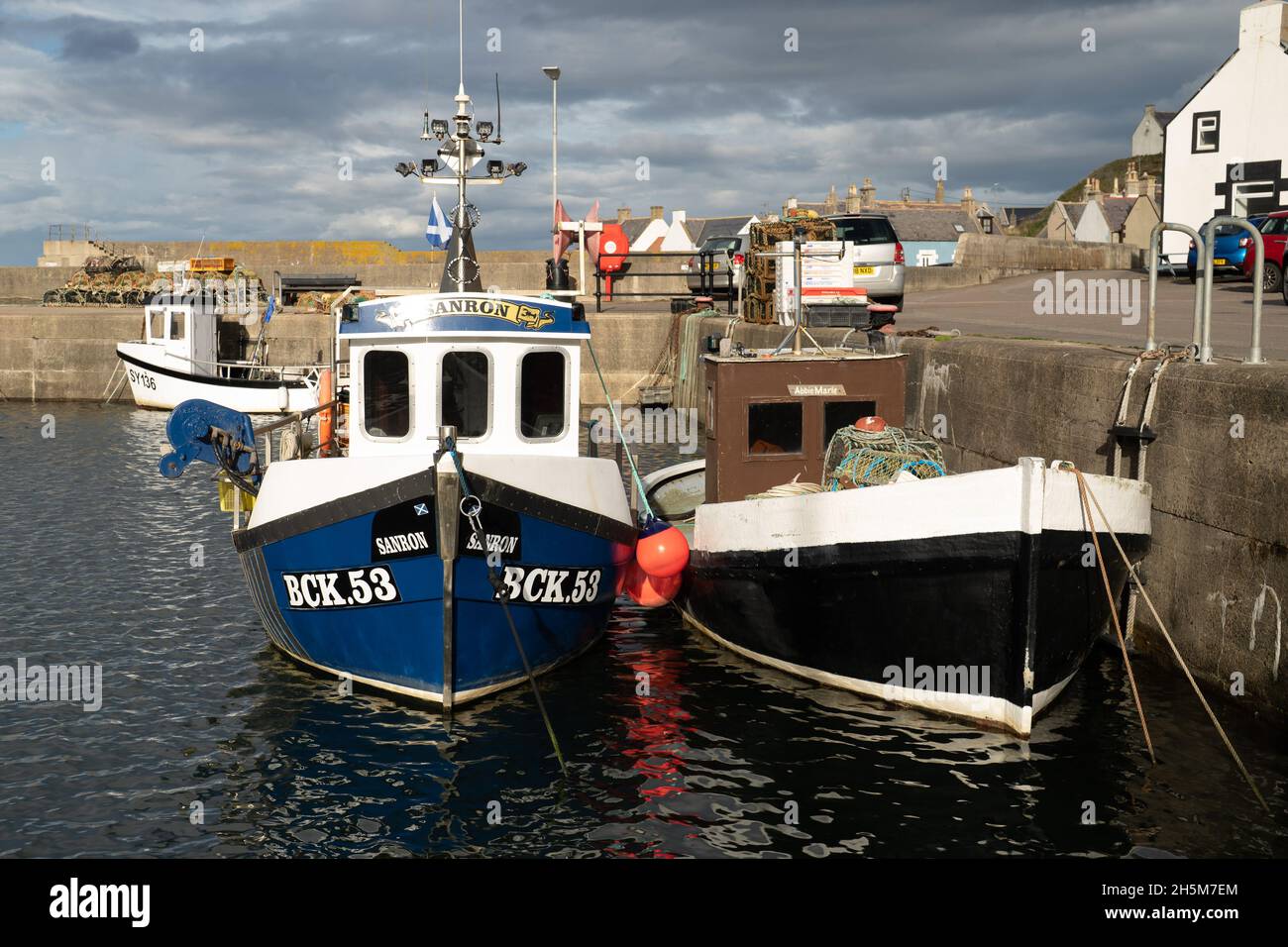 FINDOCHTY MORAY COSTA SCOZIA BARCHE DA PESCA ALL'INTERNO DEL PORTO BIANCO CHIESA E CASE SULLA COLLINA Foto Stock