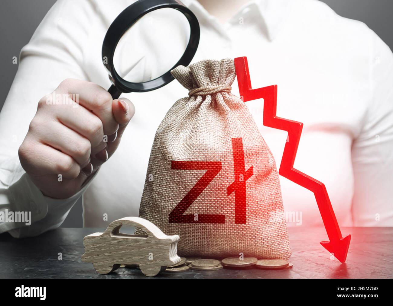 Il topografo femminile esamina un sacchetto di soldi dello zloty polacco con una freccia giù rossa ed auto. GHIACCIO. Assicurazione auto, manutenzione. Accise sul carburante. Calo delle vendite re Foto Stock