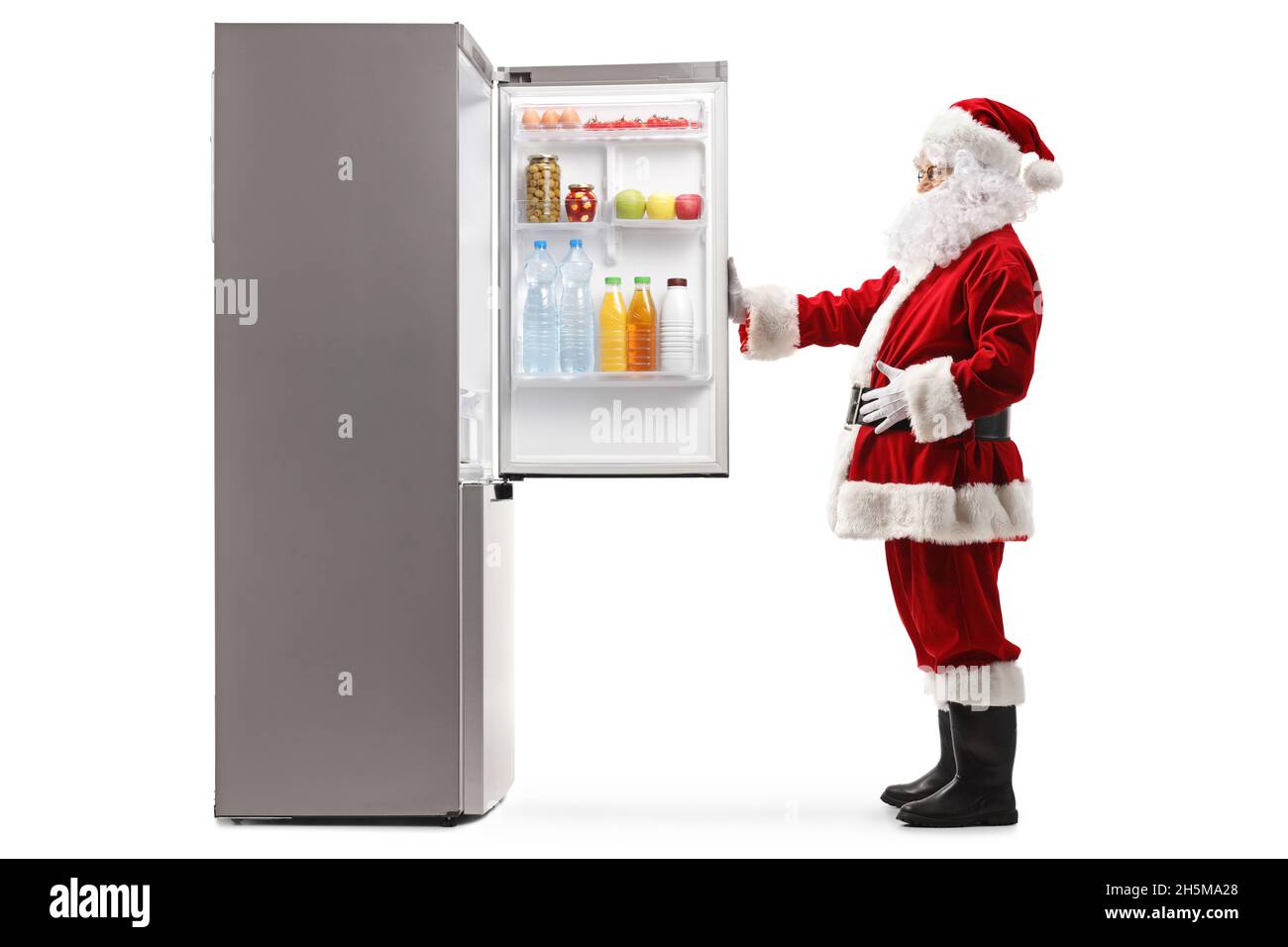 Scatto completo del profilo di Babbo Natale che apre un frigorifero pieno di cibo isolato su sfondo bianco Foto Stock
