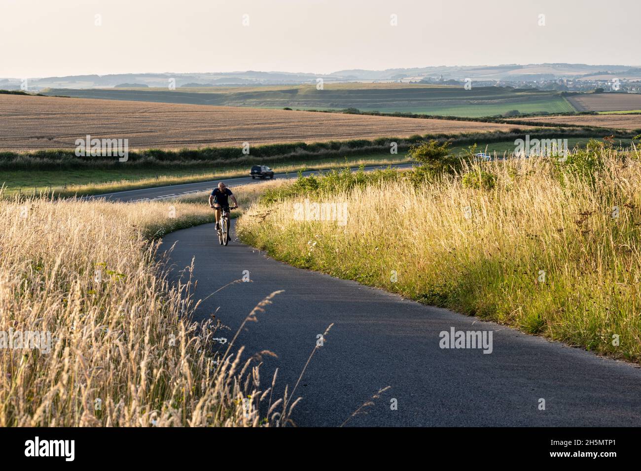 Un ciclista corre lungo la circonvallazione di Weymouth-Dorchester, accanto alla A354, sulle colline del Dorset Downs Sud. Foto Stock