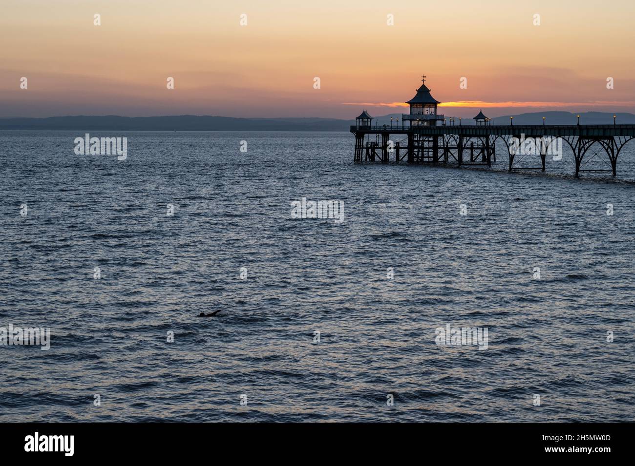 Un bagno nuota nel canale di Bristol accanto al molo di Clevedon al tramonto nel Somerset. Foto Stock