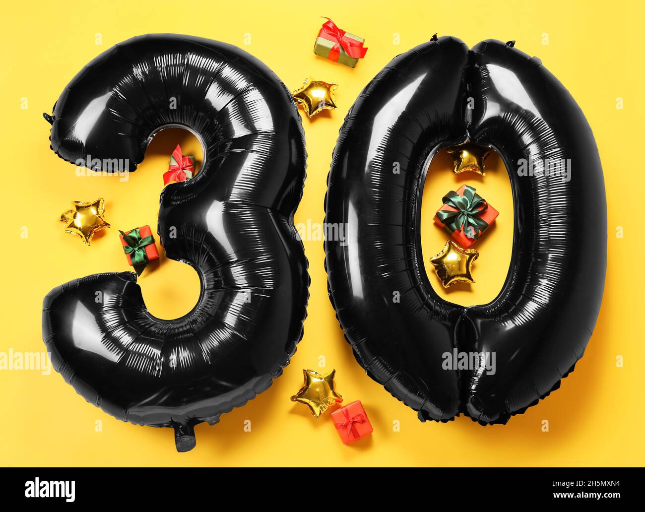 Figura 32 fatto di palloncini e scatole regalo su sfondo giallo Foto Stock