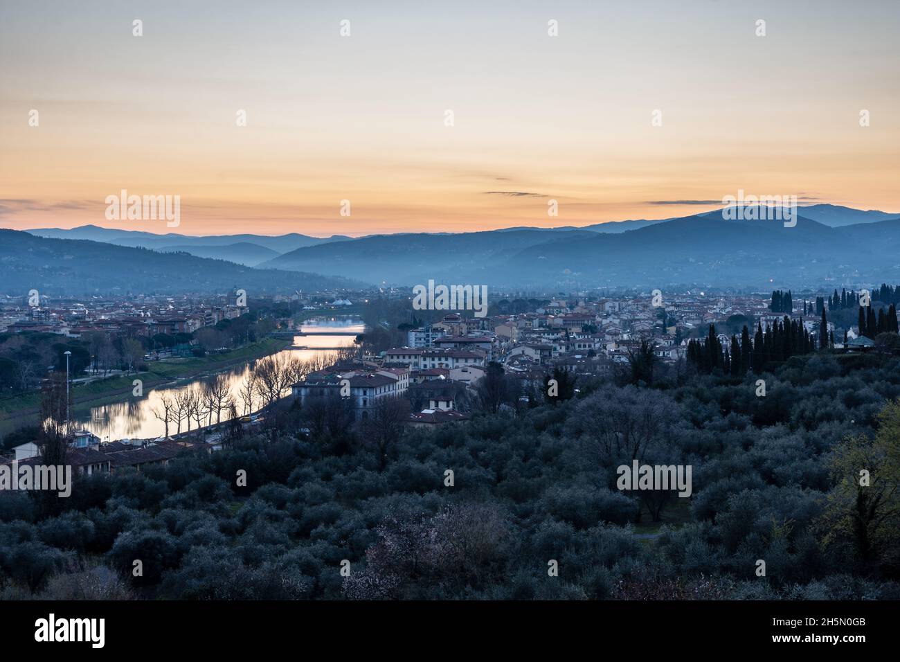 Il sole sorge lungo il fiume Arno e la periferia di Firenze, con le colline Fiesolean fornendo uno sfondo. Foto Stock