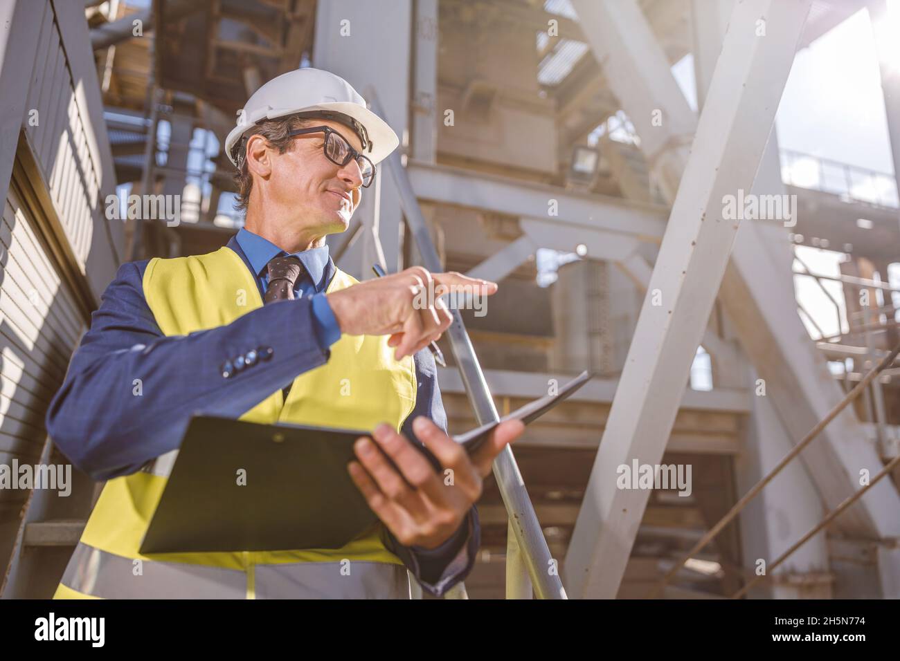 Ingegnere maschile con documenti che indicano qualcosa in fabbrica Foto Stock