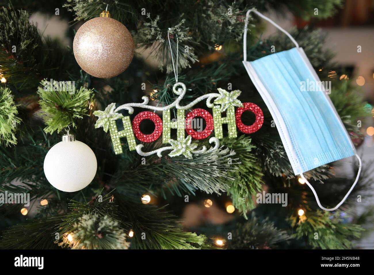 Un Natale molto allegro e vivace con bauble e maschere facciali sullo sfondo appesi all'albero di Natale Foto Stock