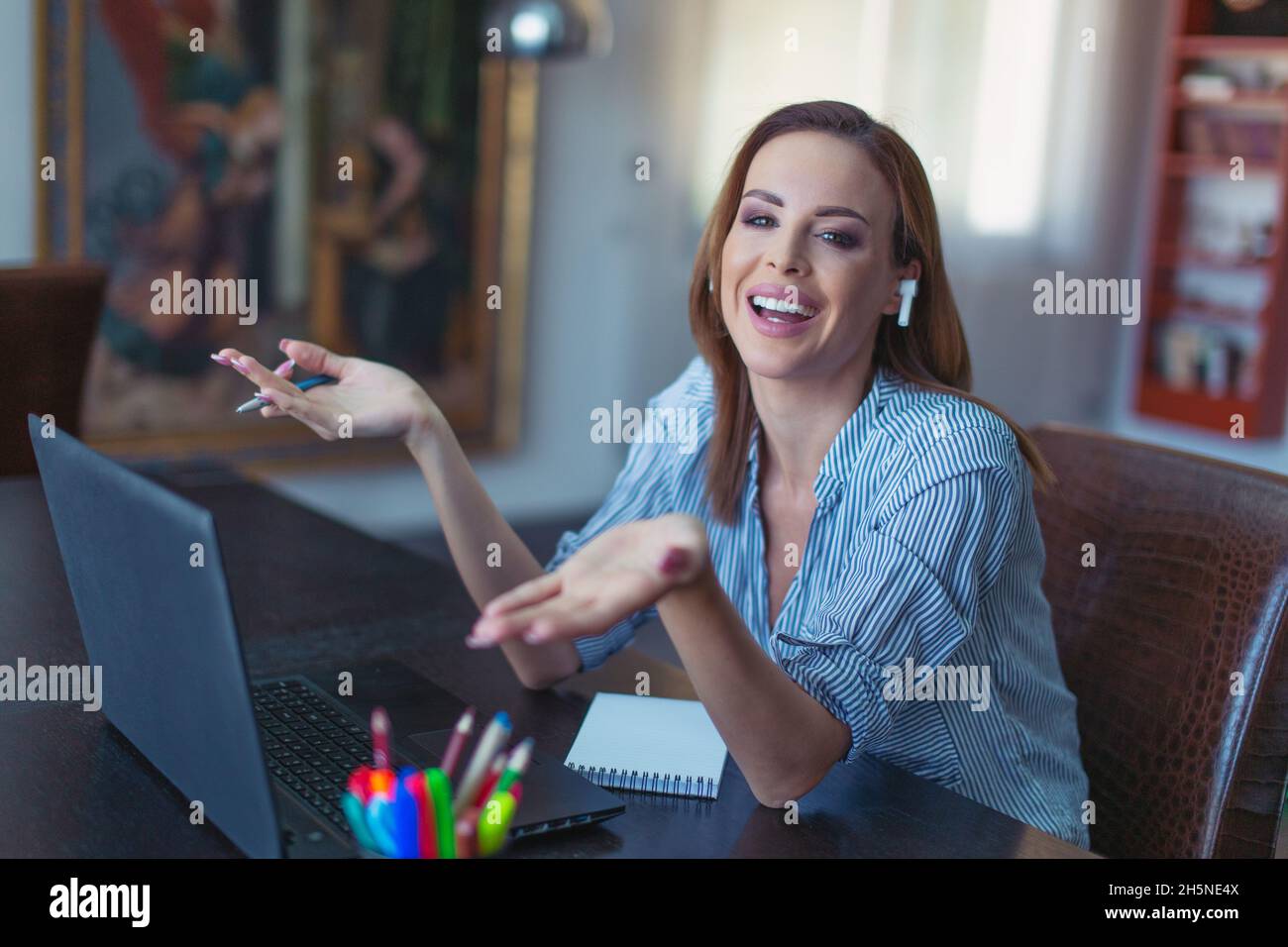 Imprenditore di successo redhead con dispositivo a mani libere che mostra soddisfazione in ufficio domestico Foto Stock
