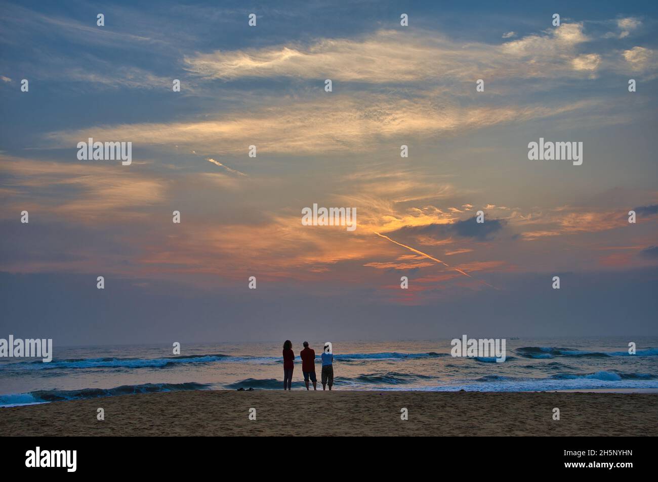 Vista al tramonto con le nuvole arancioni. Silhouette di gente vicino al mare. Mahabalipruam (Mamallapuram) è una famosa attrazione turistica nel sud di Chennai, Ind Foto Stock