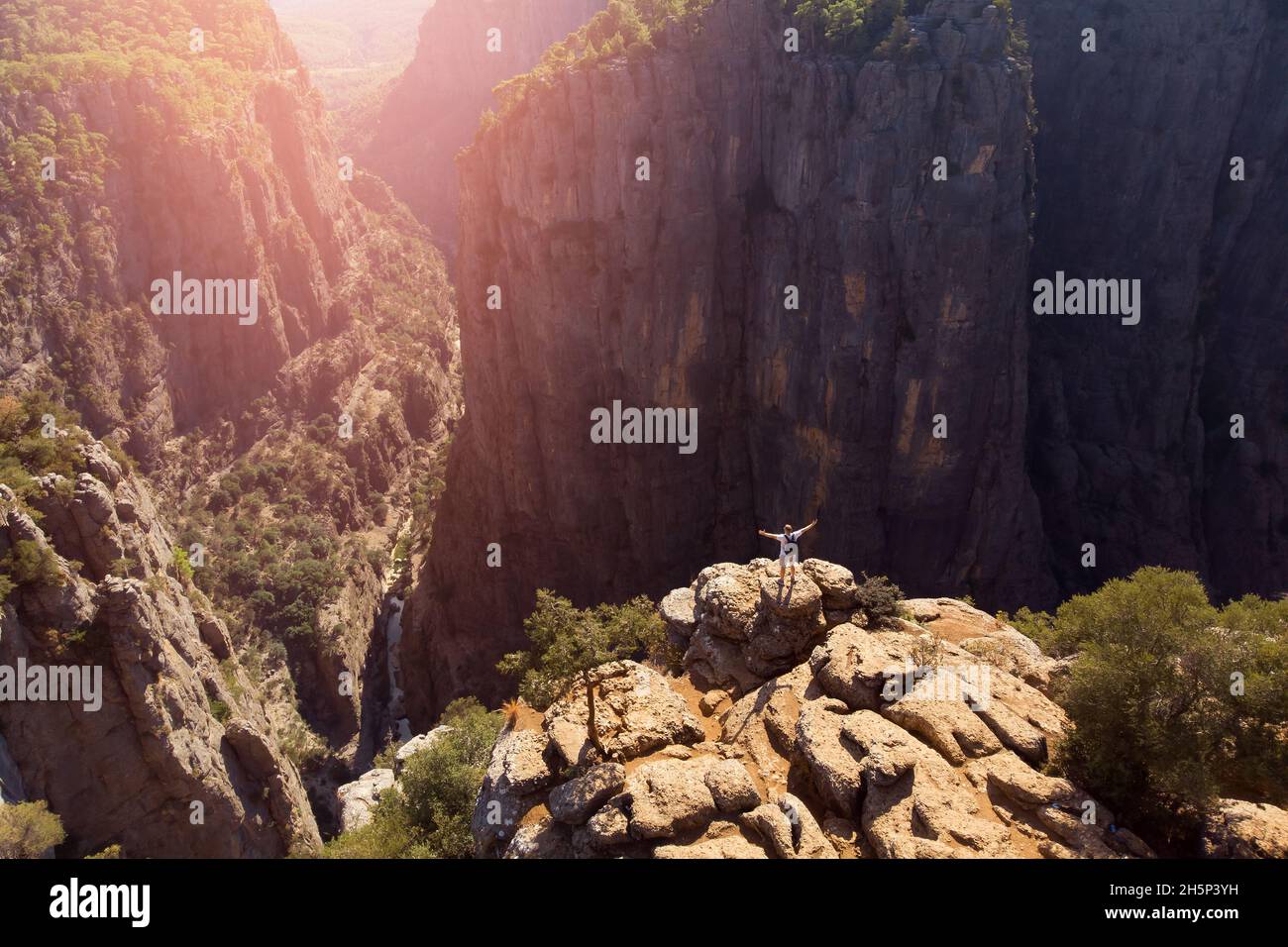 Uomo viaggiatore in piedi sulla scogliera del canyon tazi Turchia con foresta aerea vista dal cielo drone con tramonto. Concetto di viaggio stile di vita avventura libertà da solo. Foto Stock