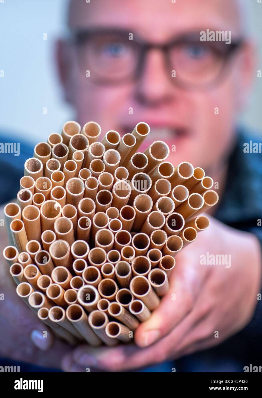 PRODUZIONE - 25 ottobre 2021, Meclemburgo-Pomerania occidentale, Kröpelin: Hannes Subklew, uno dei fondatori della start-up Rohalm, detiene un fascio di cannucce riutilizzabili in canna. L'azienda produce le paillette lavabili in lavastoviglie da un anno. Dal divieto della plastica monouso, i ristoratori e gli organizzatori di partito cercano prodotti sostenibili alternativi. Nelle officine per disabili, la canna, lunga più di due metri, viene tagliata, pulita e levigata e ogni settimana vengono consegnate diverse migliaia di cannucce da bere con diametri diversi. (A dpa 'Drinkin Foto Stock