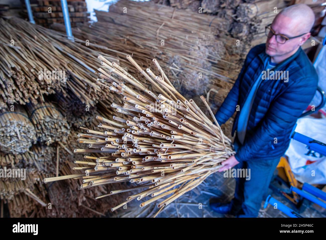 PRODUZIONE - 25 ottobre 2021, Meclemburgo-Pomerania occidentale, Kröpelin: Hannes Subklew, uno dei fondatori della start-up Rohalm, controlla la qualità della canna per la produzione di cannucce riutilizzabili. L'azienda produce le paillette lavabili in lavastoviglie da un anno. Dal divieto della plastica usa e getta, i ristoratori e gli organizzatori del partito cercano prodotti sostenibili alternativi. Nelle officine per disabili, la canna lunga più di due metri viene tagliata, pulita e levigata e vengono consegnate alla settimana diverse migliaia di cannucce da bere con diametri diversi. (a dpa Foto Stock