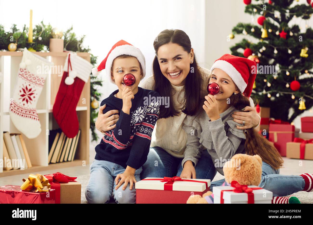 Felice, sorridente madre e bambini che si divertono insieme la mattina di Natale a casa Foto Stock