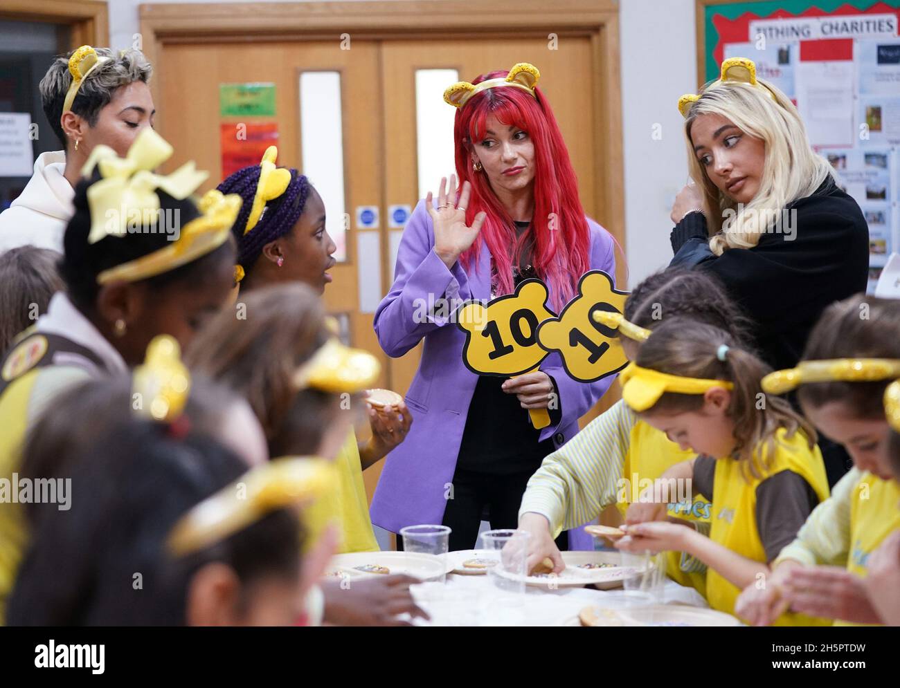 Rigorosamente venire ballerini professionisti Karen Hauer (a sinistra) e Dianne Buswell (centro), con l'ex concorrente Saffron Barker Strictly come Dancing giudicare i risultati del biscotto decorando da un gruppo di Brownies e Girl Guides, alla Brentford Free Church a Brentford, a ovest di Londra. Data foto: Mercoledì 10 novembre 2021. Foto Stock