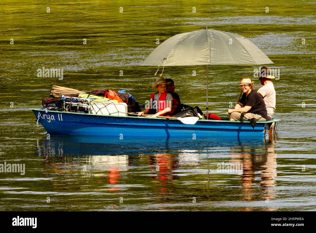 Vacanza sul fiume, persone in una barca sotto un ombrello galleggiare lungo il fiume Sassonia Germania Elba Foto Stock