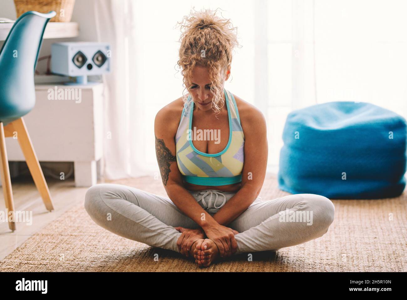 Allenamento fitness lifestyle a casa giovane donna adulta seduta sul tappeto in posizione balsamo come yoga o pilates. Le donne adulte riposano e si rilassano Foto Stock