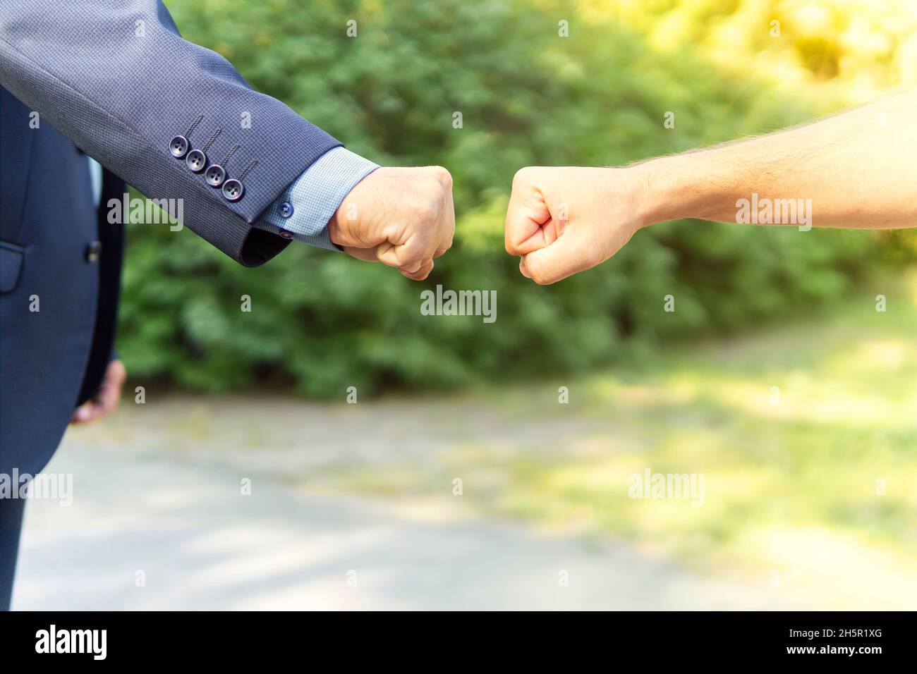 Gesti delle mani. Il primo saluto è un'alternativa a una stretta di mano. Il pugno che batte come saluto popolare tra i migliori amici. Stretta di mano contro il parco verde Bac Foto Stock
