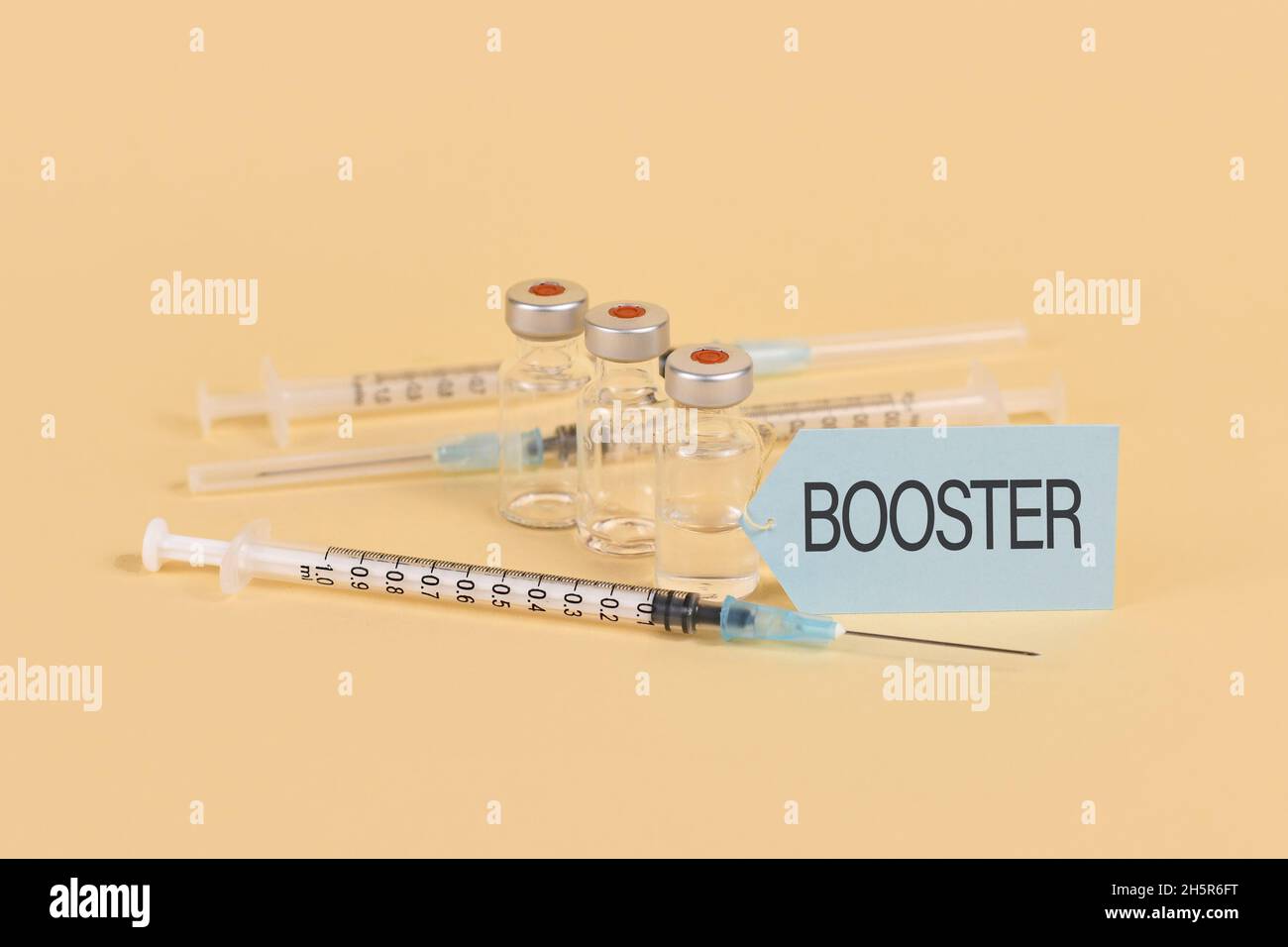 Concetto per la vaccinazione di richiamo del virus Corina con 3 flaconcini e siringhe su sfondo giallo Foto Stock