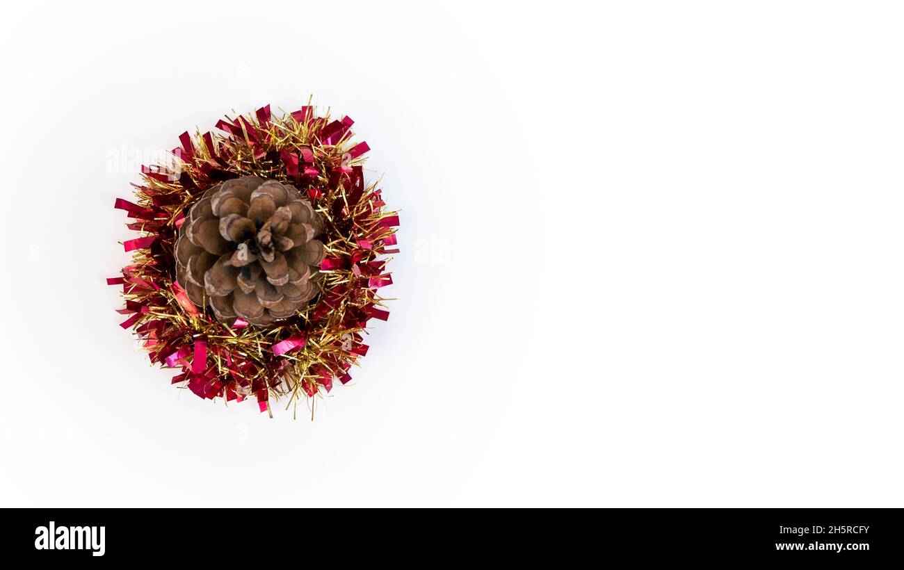 Bellissimo fiore pinecone con un Natale tinsel per decorazioni tradizionali in inverno. Coni di pino xmas e garland nastro isolato su backgrou bianco Foto Stock