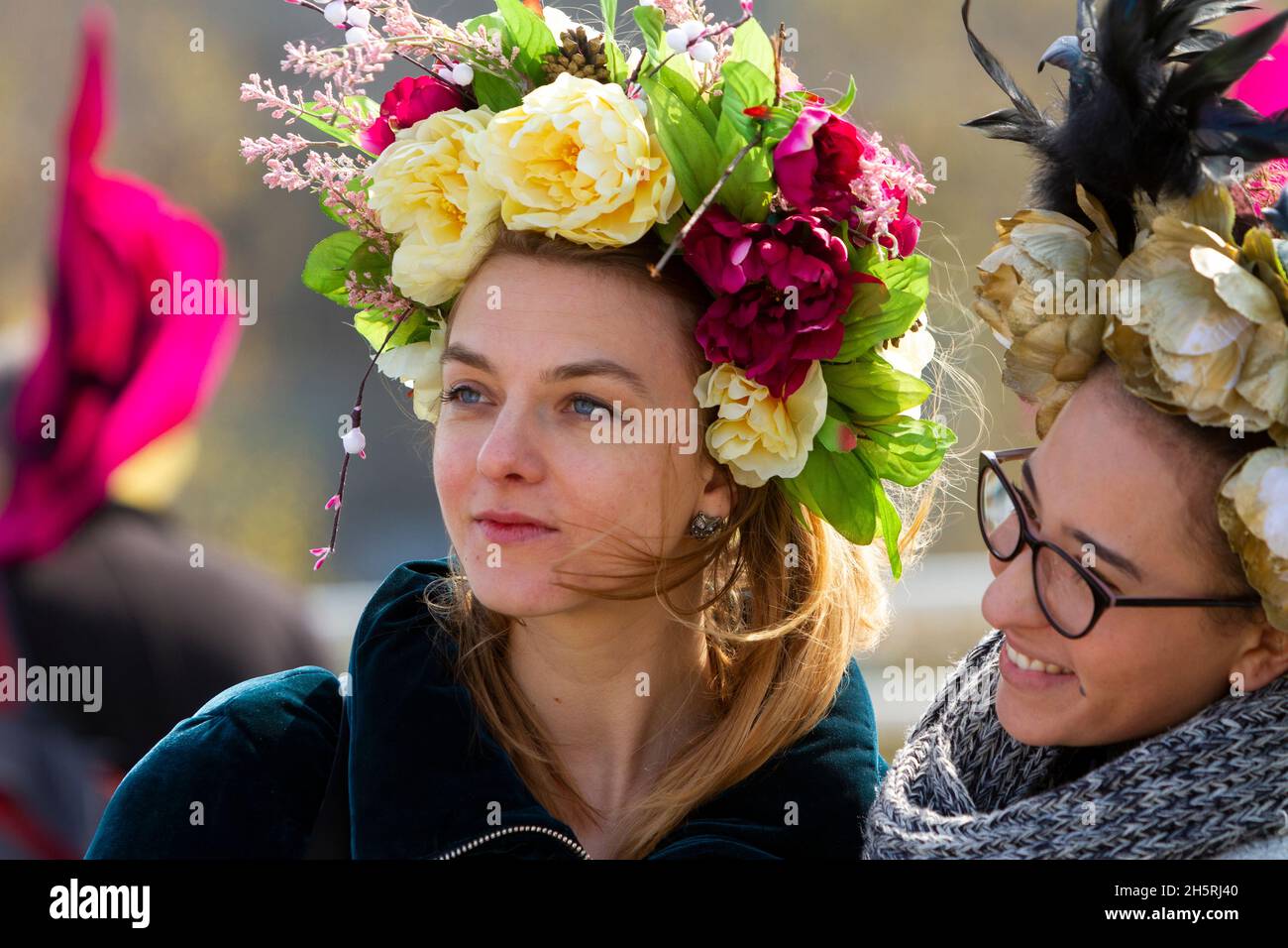 Ritratto di strada di due giovani donne ad una dimostrazione di cambiamento climatico entrambi indossando grandi headdresses floreali. Entrambi sono vicini e guardano a sinistra. Foto Stock