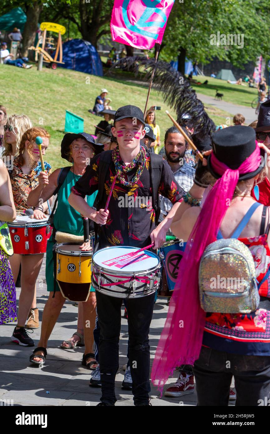 Foto di strada di samba band in una dimostrazione di cambiamento climatico. Un giovane batterista è un'immagine centrale con altri dietro, bandiere e leader della band. Foto Stock