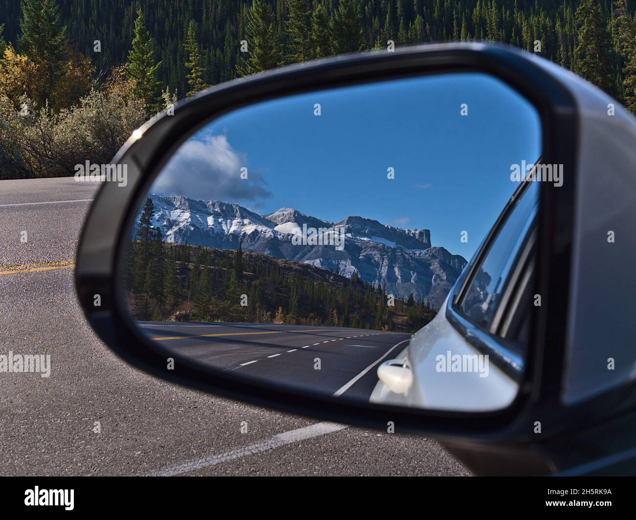 Vista mozzafiato della Yellowhead Highway nel Jasper National Park, Alberta, Canada attraverso lo specchio laterale di un'auto bianca con foresta e le Montagne Rocciose. Foto Stock