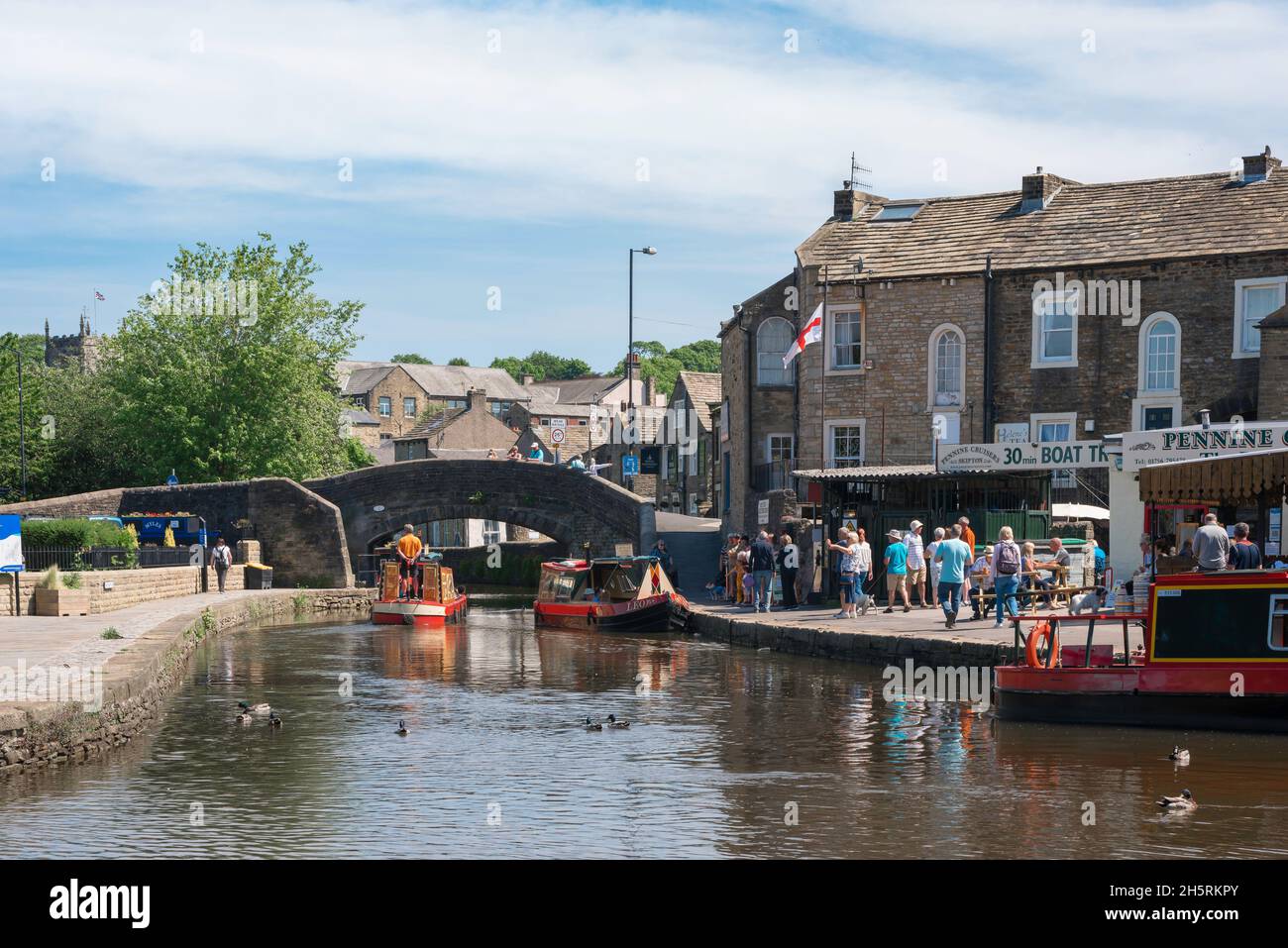 Canal UK, guarda in estate una stretta barca che naviga verso il canale Springs Branch nel centro storico di Skipton, North Yorkshire, Inghilterra, Regno Unito Foto Stock