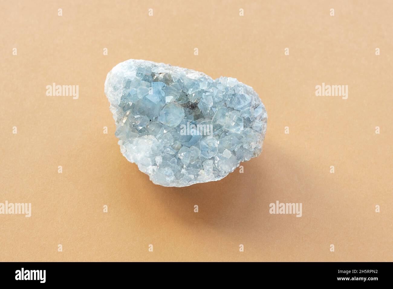 Pietra cristallina blu celestine gemma minerale. Cristalli naturali azzurri ruvidi Celestite cluster su sfondo beige, primo piano. Vista dall'alto Foto Stock