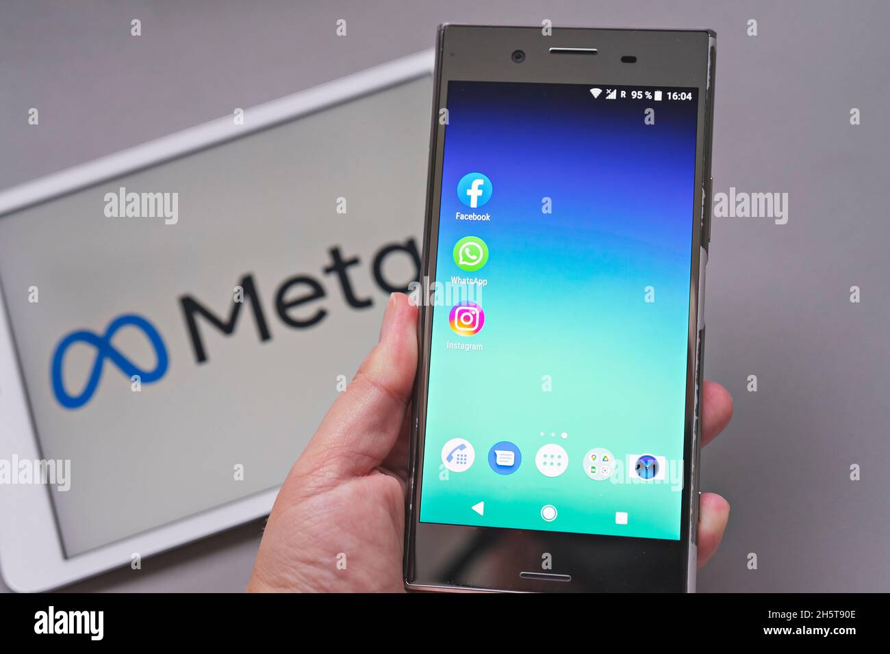 Display mobile con logo delle app Facebook, WhatsApp e Instagram in fronte a UN META logotipo sfocato su sfondo bianco Foto Stock